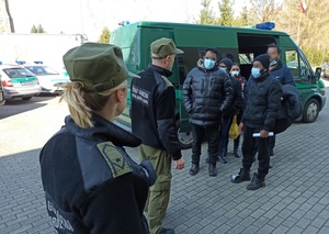 Dwóch funkcjonariuszy Straży Granicznej pilnuje cudzoziemców