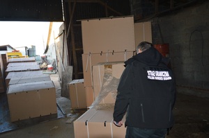 Kartony wypełnione tytoniem Funkcjonariusz Straży Granicznej stoi w magazynie koło wielu ogromnych kartonów wypełnionych tytoniem