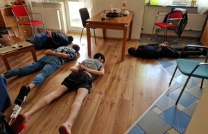 Zatrzymani za przyrzut ludzi przez granicę dwóch mężczyzn lezy na podłodze na brzuchu, ręce mają skrępowane na plecach kajdankami