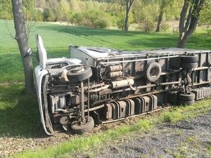 Poszkodowany kierowca utknął w kabinie przewróconego auta w rowie, na boku  leży TIR białego koloru