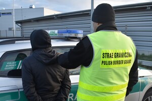 Funkcjonariusz Nadodrzańskiego Oddziału Straży Granicznej z zatrzymanym kierowcą przy samochodzie służbowym Straży Granicznej Funkcjonariusz Nadodrzańskiego Oddziału Straży Granicznej z zatrzymanym kierowcą przy samochodzie służbowym Straży Granicznej